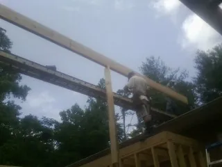Carpenter setting a ridge beam over a new addition frame — Ice Dam Removal by Roofing Brothers in Iowa Falls