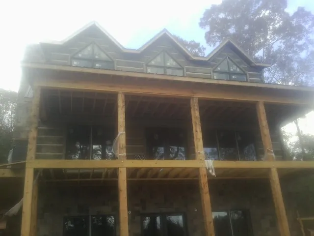 Dormers and porch framing on a large log home under construction — Roof Coating work by our crew in Iowa Falls