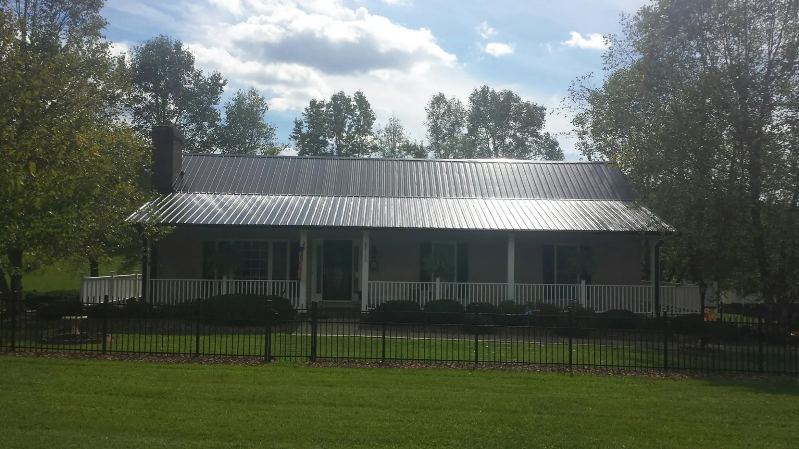 Gray metal roof on a brick ranch with a full width front porch — Gutter Guard Installation work by our crew in Iowa Falls