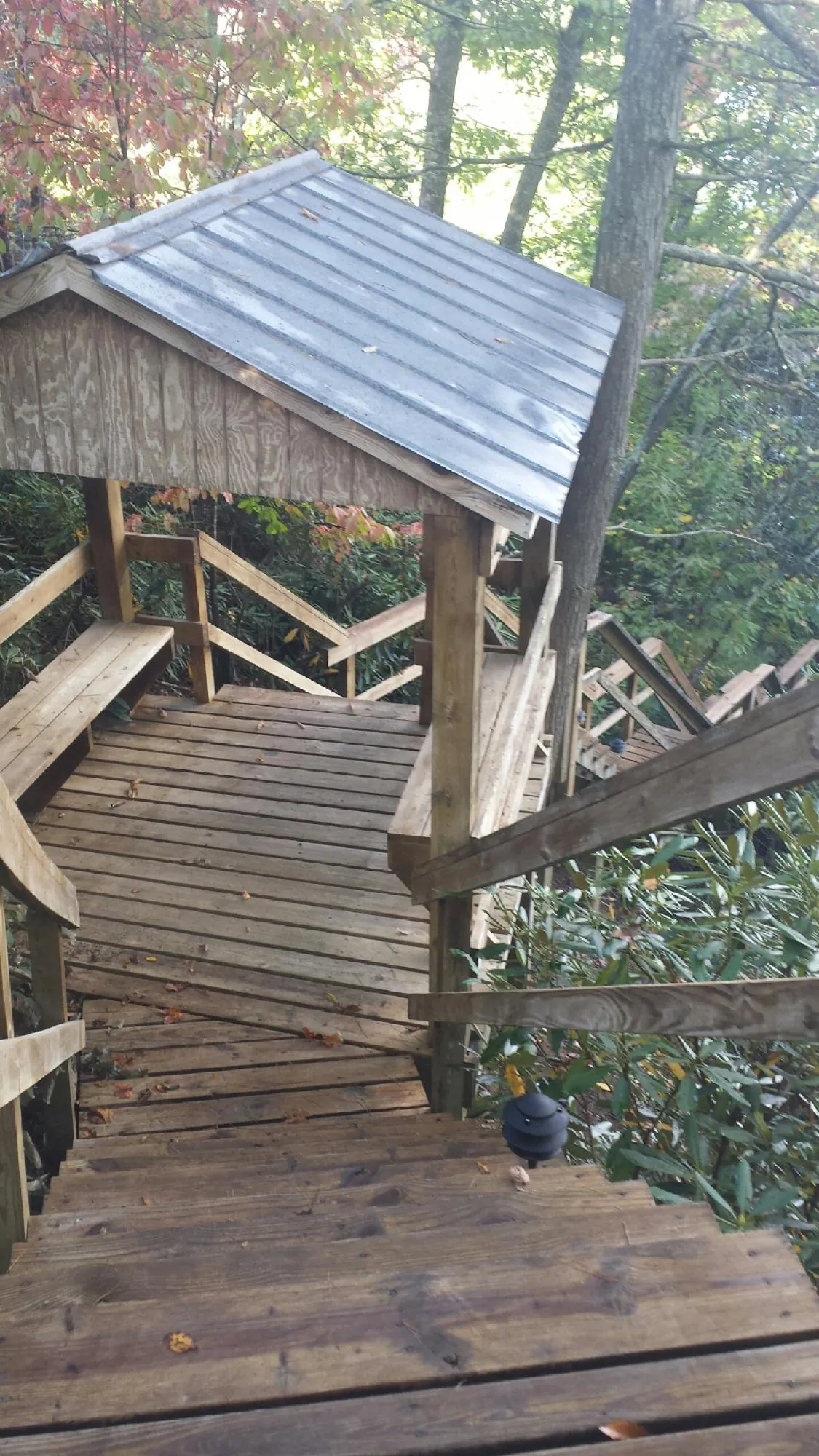 Metal roofed shelter over wooden steps on a wooded walkway — Skylight Repair & Installation work by our crew in Iowa Falls