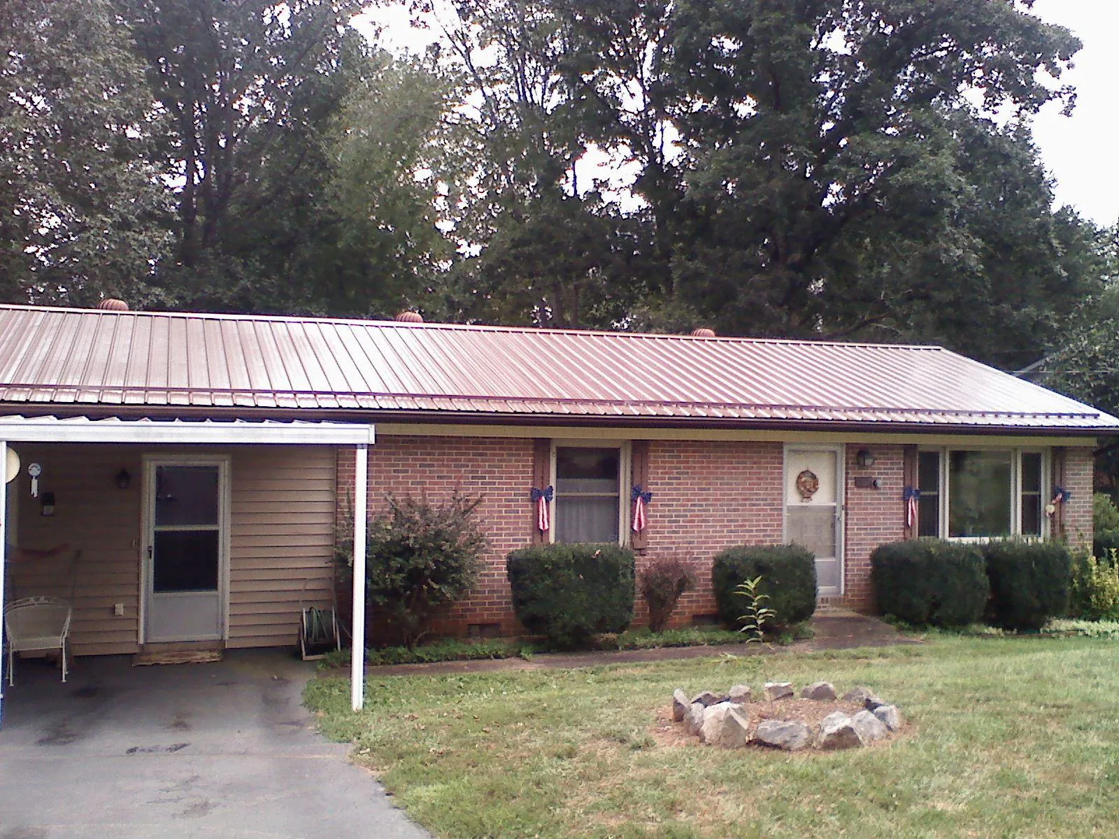 Bronze metal roof and carport on a brick ranch home — Roof Repair work by our crew in Iowa Falls