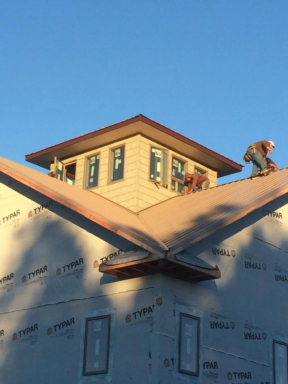 Roofers working around a rooftop cupola on a new metal roof at sunset — Roof Waterproofing in Iowa Falls by Roofing Brothers